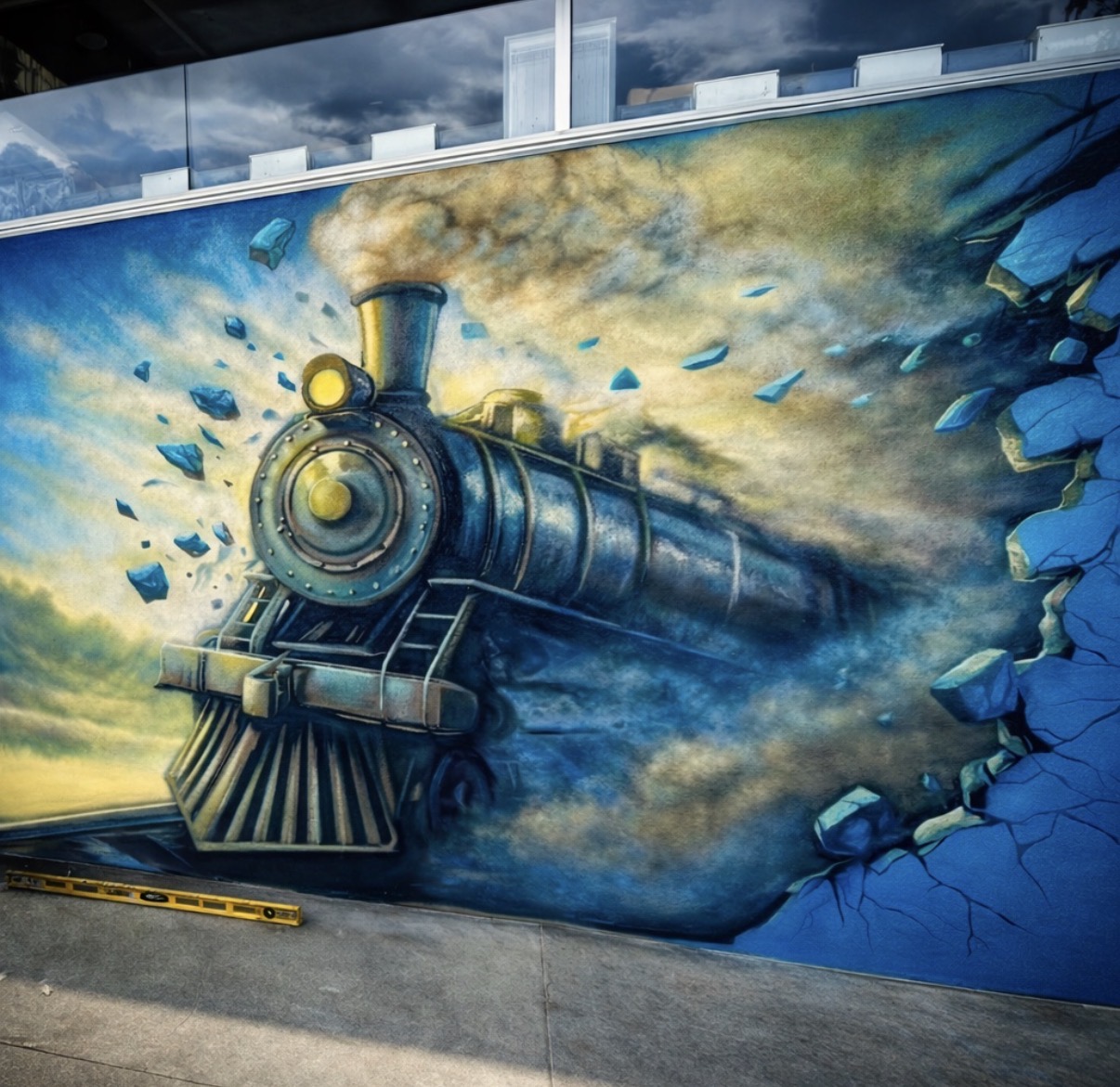 Steam locomotive mural appearing to break through a blue wall